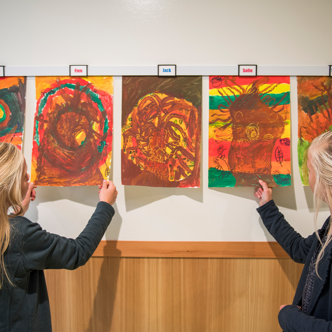 Kinderen met tekeningen aan schoolwand 