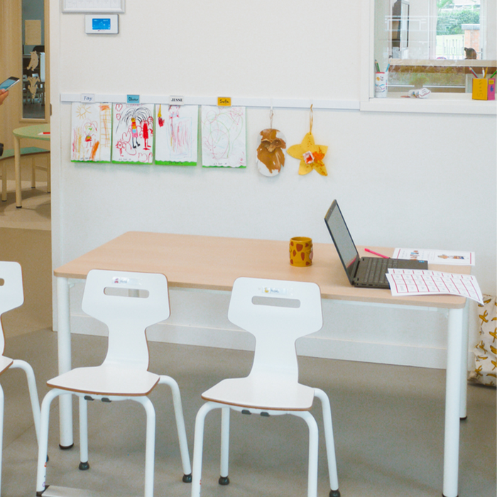 Tekeningen en knutselwerkjes van leerlingen hangen aan een Artiteq Info Rail boven een werktafel, voor een creatieve en flexibele aankleding van het klaslokaal.