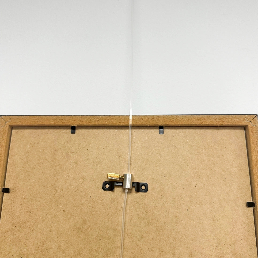 Artiteq Ophanghaak Rond Messing 5kg aan houten fotolijst